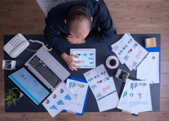 Homem sentado analisando diversos gráficos em um tablet.