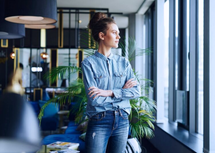Mulher em pé de braços cruzados em um escritório.