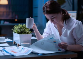 Mulher analisando relatórios com dados e informações financeiras da empresa.