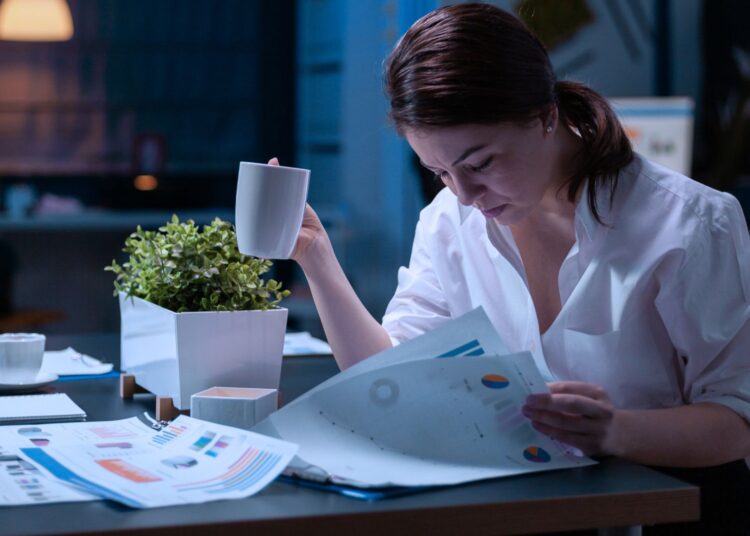 Mulher analisando relatórios com dados e informações financeiras da empresa.