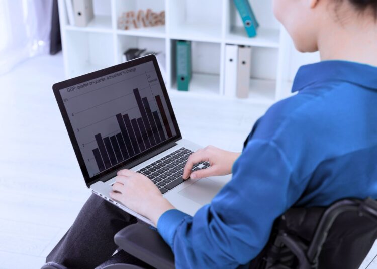Pessoa sentada analisando um gráfico na tela do notebook.