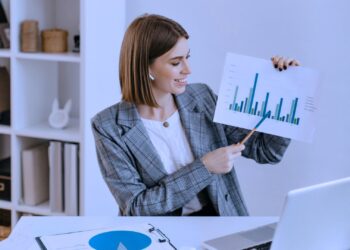 Mulher segurando uma folha impressa com um gráfico. Ela está apresentando algumas informações.