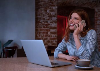 Mulher sorrindo enquanto trabalha em casa.