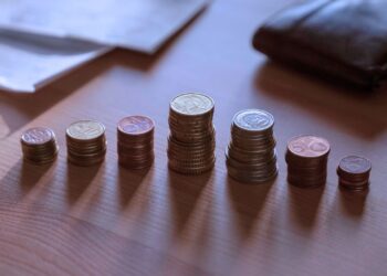 Várias moedas empilhadas sobre uma mesa.