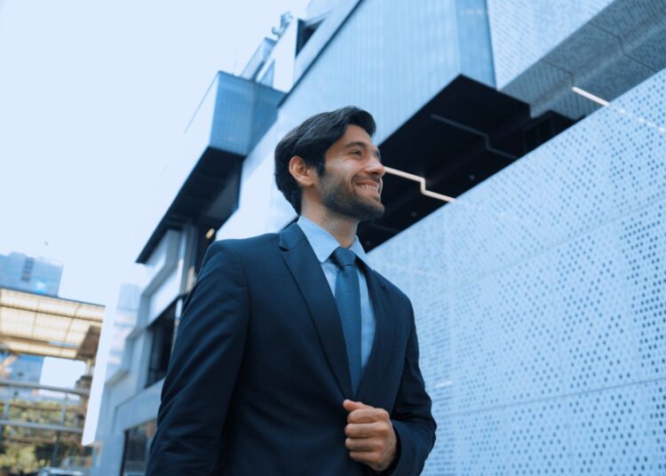 Homem de terno sorrindo enquanto anda pela rua.