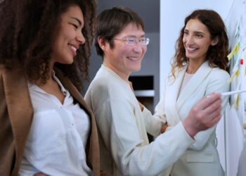 Um homem e duas mulheres sorrindo enquanto estruturam um planejamento.