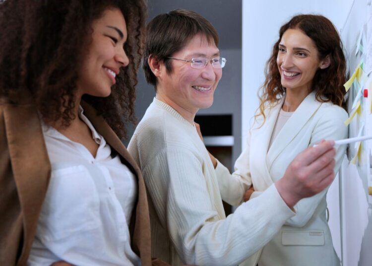 Um homem e duas mulheres sorrindo enquanto estruturam um planejamento.