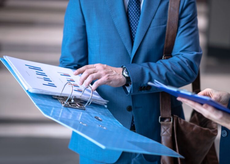 Homem segurando um relatório com gráficos impressos.