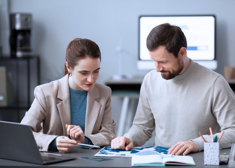 Uma mulher e um homem analisando indicadores financeiros no escritório.