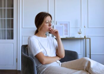 Mulher pensativa sentada em um sofá.