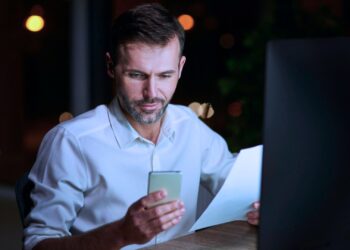 Homem olhando para o celular que está na sua mão.