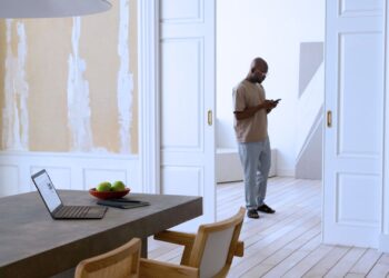 Homem mexendo no celular na sala de sua casa.