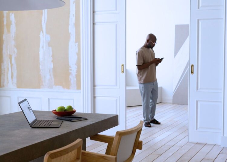 Homem mexendo no celular na sala de sua casa.