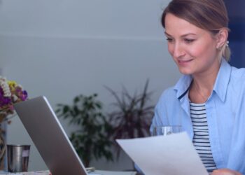 Mulher analisando suas finanças no notebook.