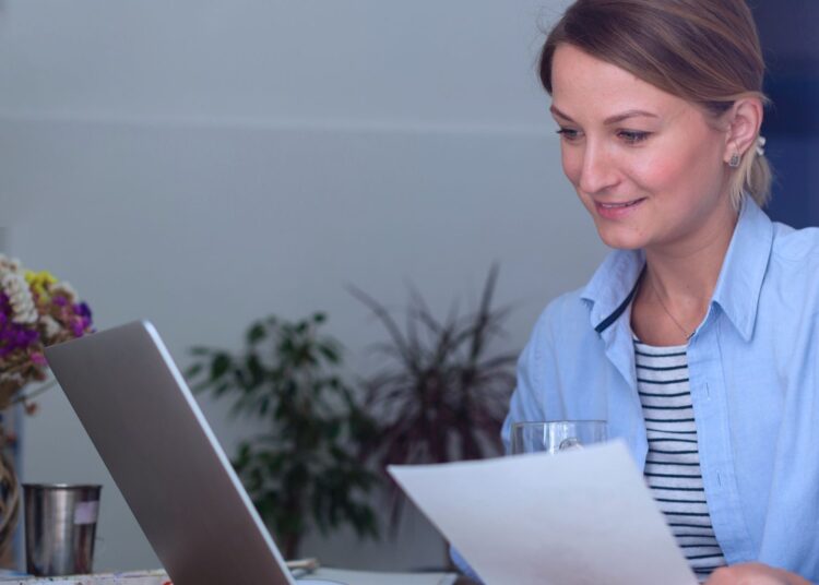 Mulher analisando suas finanças no notebook.