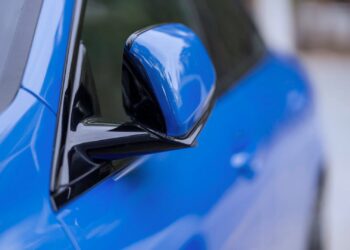 Close-up do retrovisor de um carro azul, representando empréstimos com garantia de veículo e soluções financeiras relacionadas ao setor automotivo.