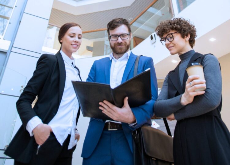 Grupo de profissionais discutindo relatórios financeiros em um ambiente corporativo, destacando colaboração e análise de dados de liquidez corrente.