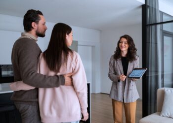 Corretora apresentando um imóvel a um casal interessado, representando estratégias de investimento em imóveis.