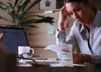 Mulher analisando documentos financeiros em um escritório, representando o conceito de despesas antecipadas.