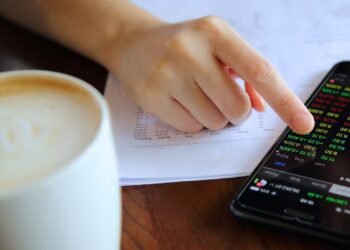 Pessoa analisando dados financeiros em um smartphone, com gráficos coloridos, representando o conceito de liquidez seca.