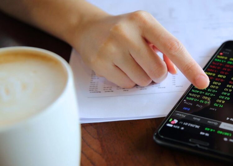 Pessoa analisando dados financeiros em um smartphone, com gráficos coloridos, representando o conceito de liquidez seca.
