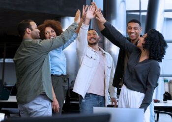 Equipe de trabalho comemorando sucesso com um high five coletivo, simbolizando união, motivação e reconhecimento no ambiente corporativo.