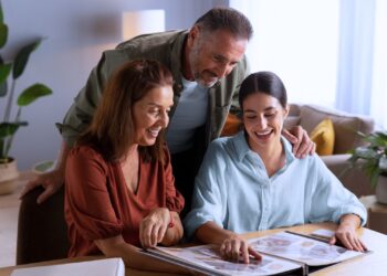 Um momento de conexão familiar enquanto três gerações revisitam memórias preciosas em um álbum de fotos, compartilhando sorrisos e histórias significativas.