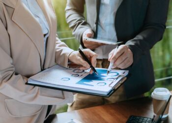 Profissionais analisando gráficos e dados financeiros em ambiente corporativo, simbolizando visão sistêmica e gestão estratégica.