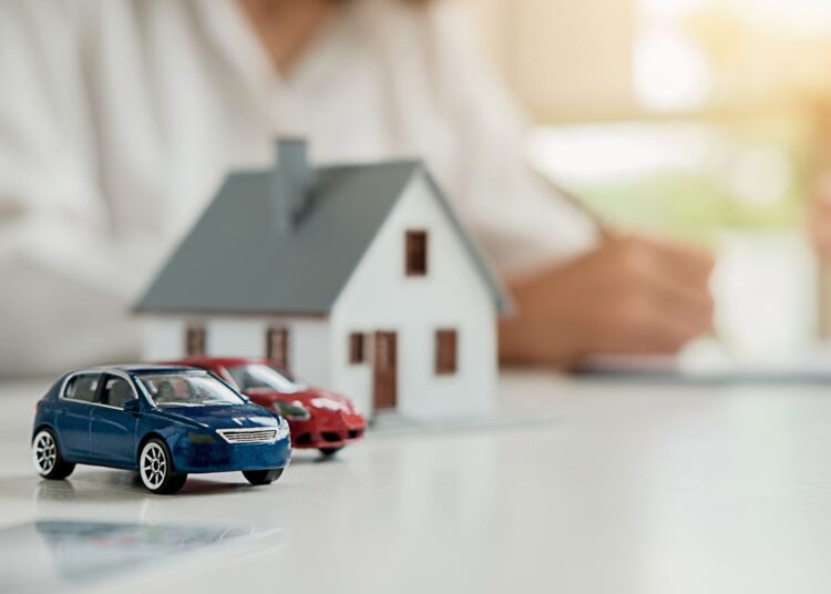 Miniaturas de carros e casa simbolizando bens usados como garantia em contratos de alienação fiduciária.