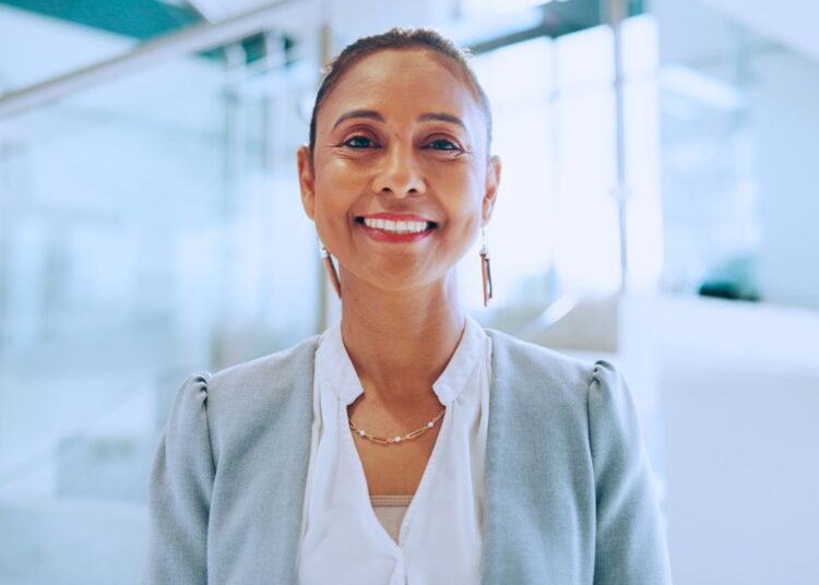 Mulher profissional sorridente em ambiente corporativo, representando a presença feminina no mercado de trabalho e liderança feminina.