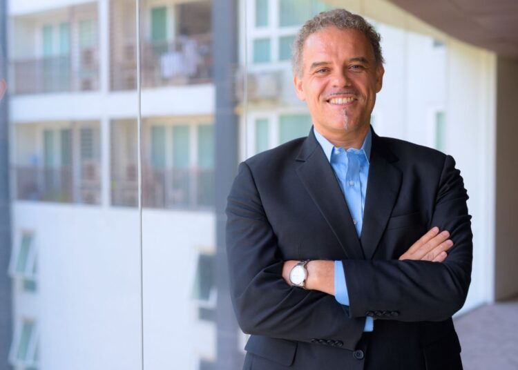 Homem de terno sorrindo com os braços cruzados, representando a figura do avalista em contratos financeiros.
