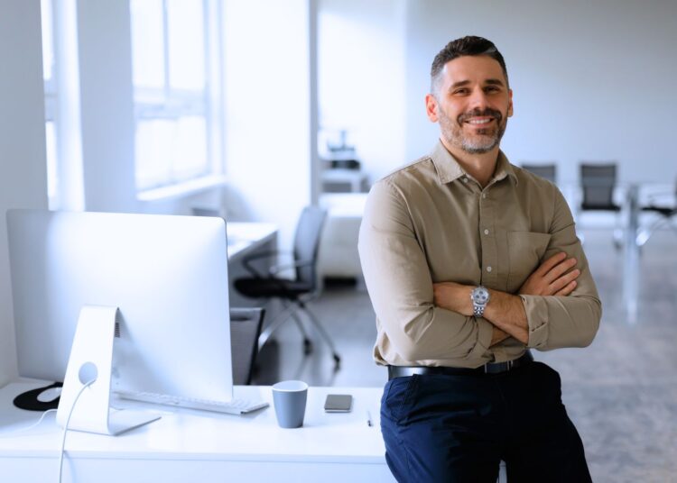 Empresário sorridente em ambiente corporativo moderno, simbolizando rentabilidade e sucesso nos negócios.