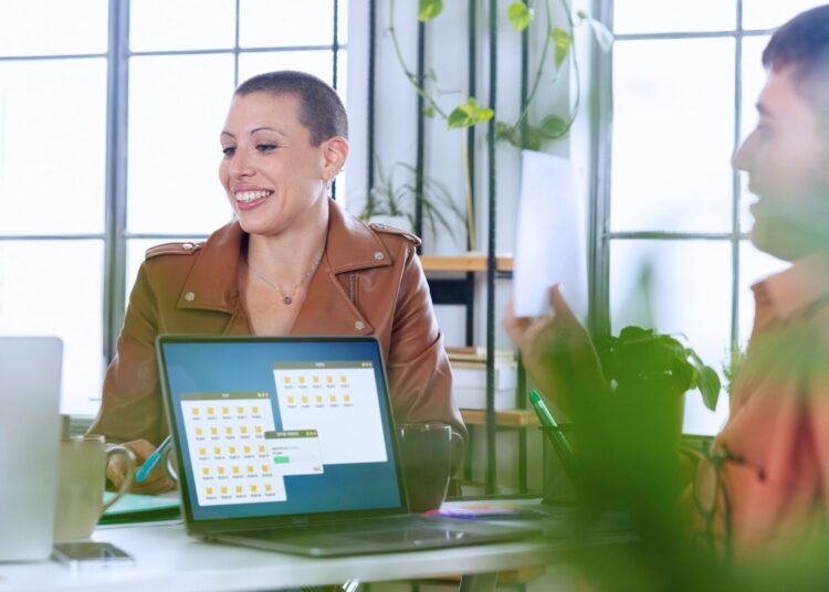 Mulher sorrindo em reunião de trabalho, representando a formalização de processos, como a averbação de imóvel, em um ambiente corporativo moderno.