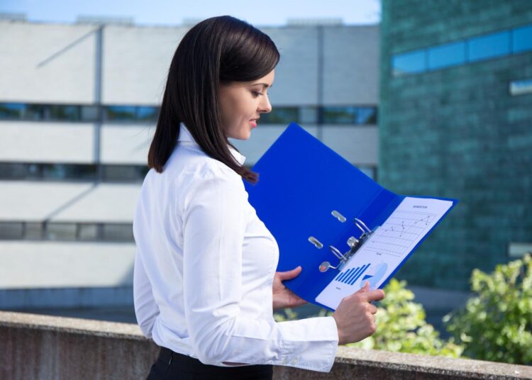 Profissional analisando gráficos financeiros em uma pasta de relatórios, representando o conceito de CAPEX e os investimentos em ativos fixos de uma empresa.